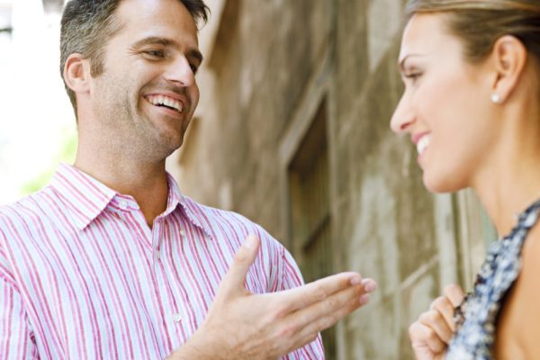 Businessman and businesswoman having an animated conversation outdoors, in a classic city.